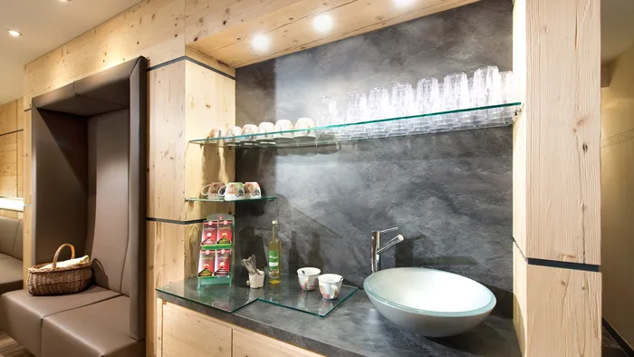 Moderne Teestation aus Holz mit Spüle, Glasregalen, Tassen und Teesorten in gemütlicher Sitzecke